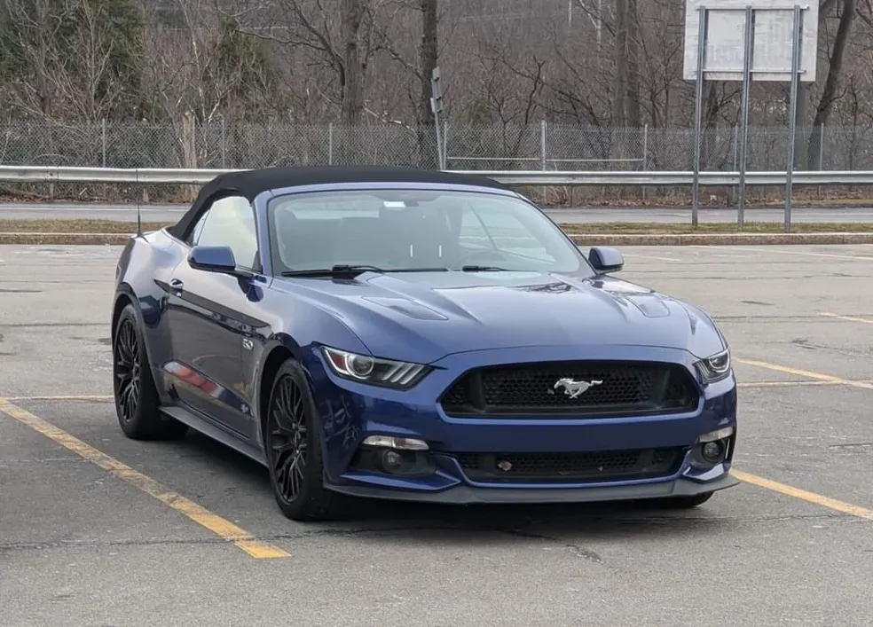 Blue Ford Mustang convertible with black top parked in empty lot