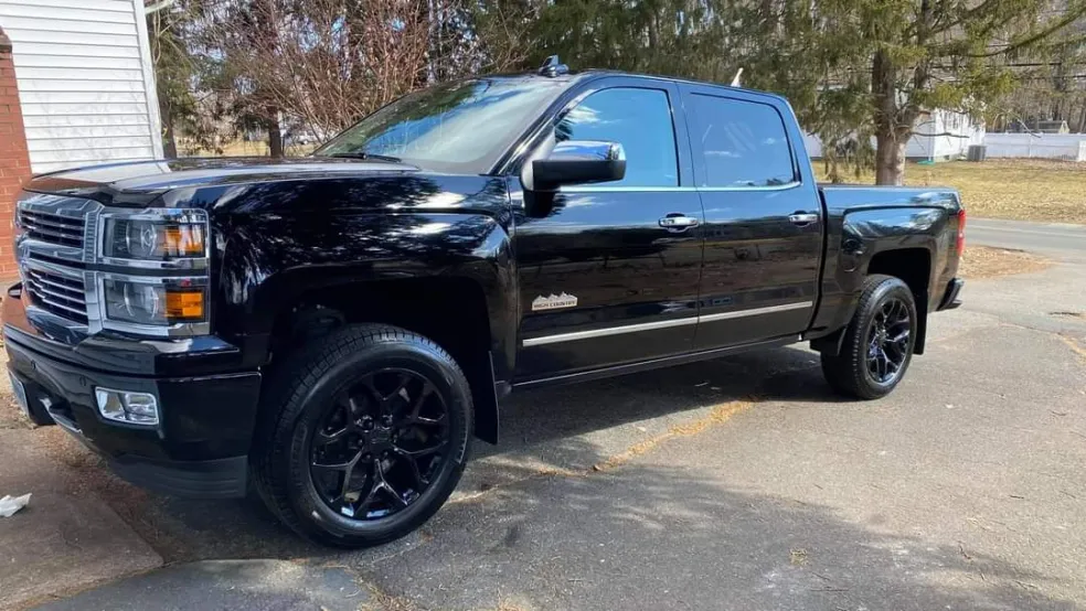 Black Chevrolet Silverado pickup truck with custom wheels parked in driveway