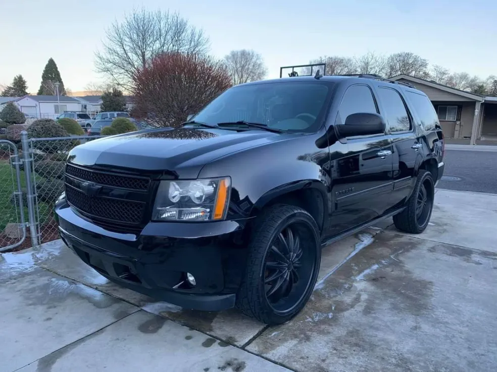 Black Chevrolet Tahoe SUV parked on driveway with residential homes visible in background