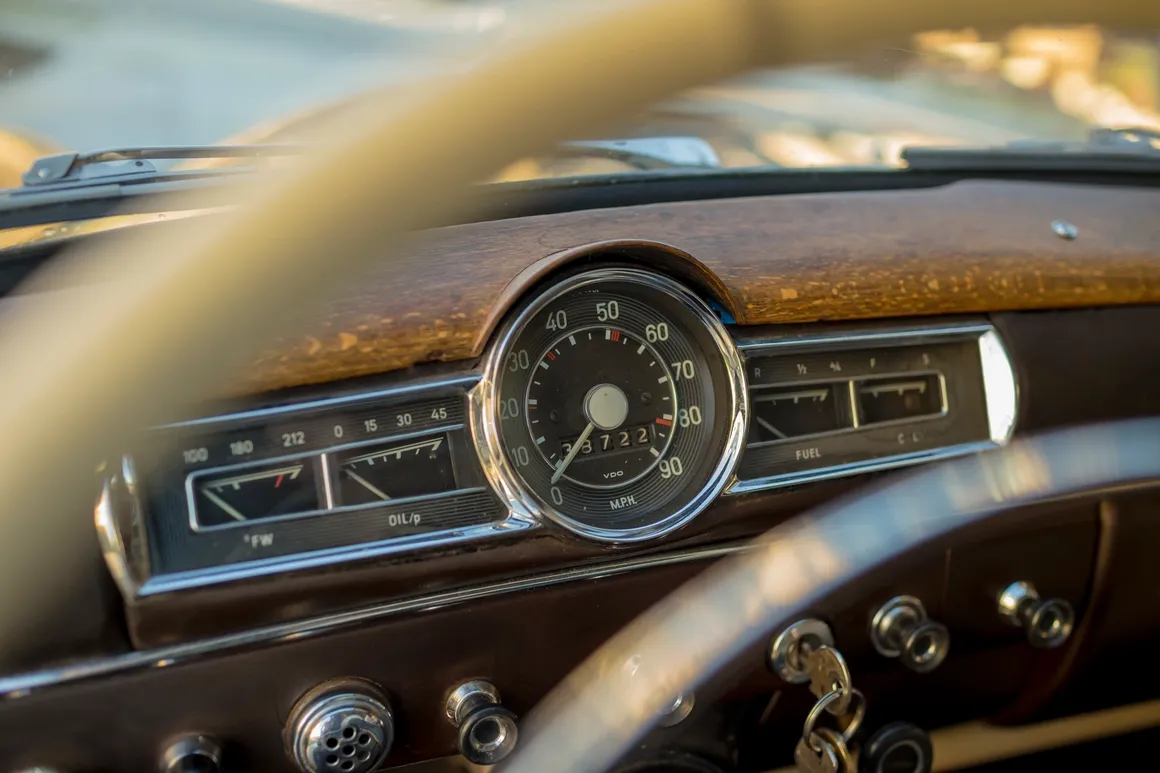 Classic car speedometer dashboard with wood grain steering wheel detail