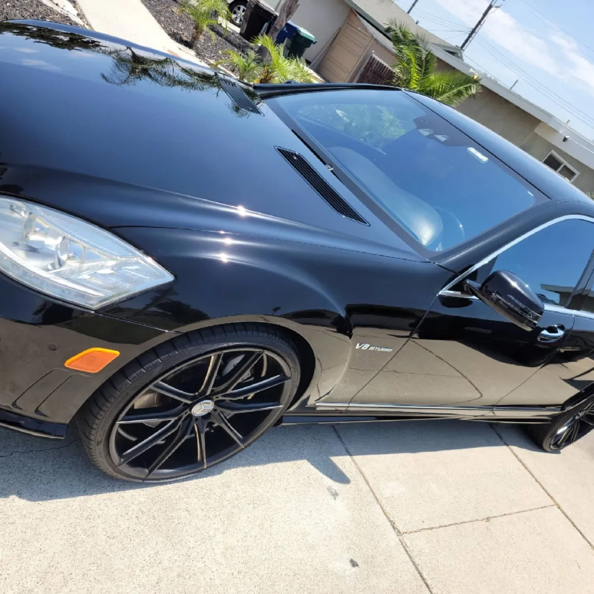 Black Mercedes-Benz sedan with custom wheels parked on residential driveway
