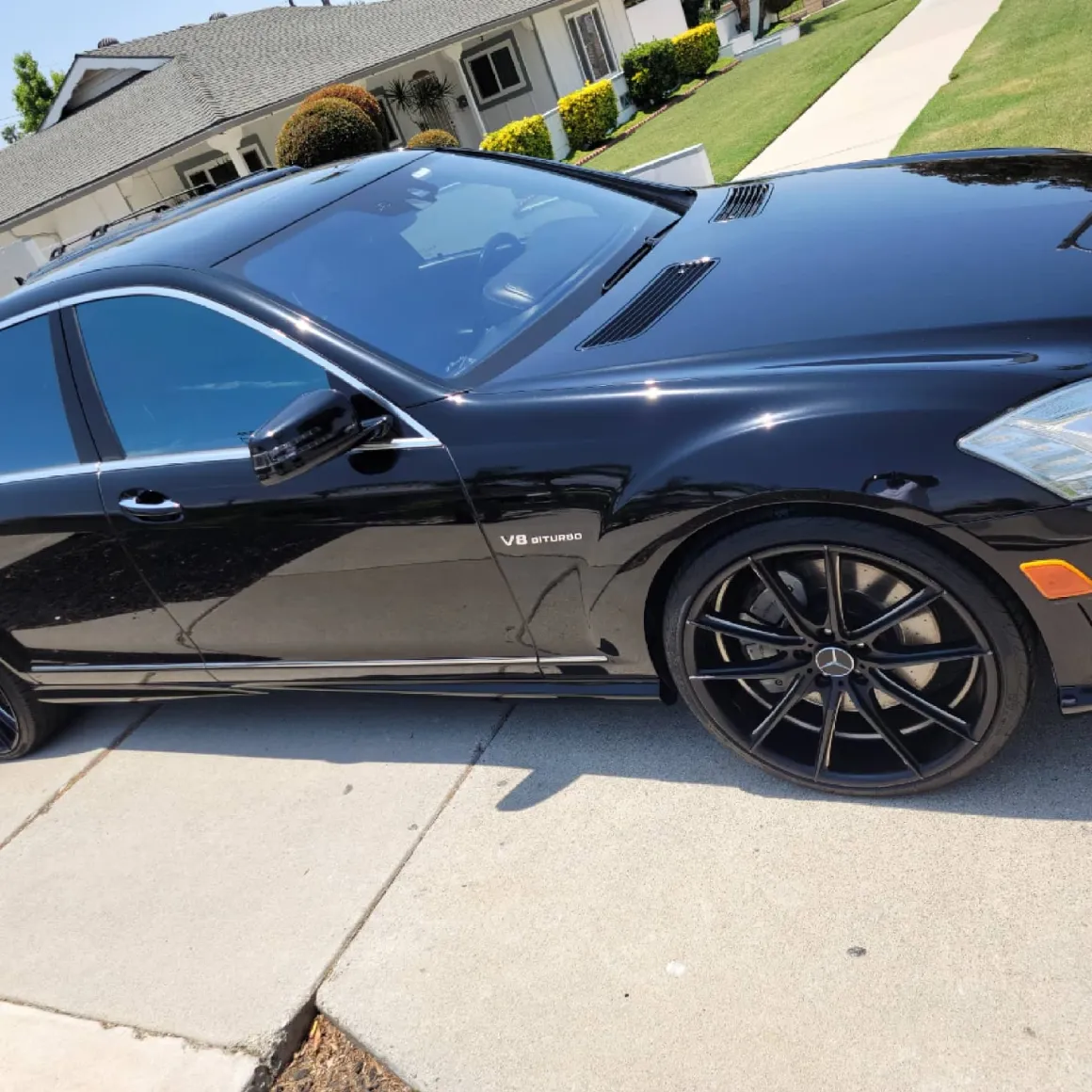 Black Mercedes-Benz V8 Biturbo with open driver door parked in driveway