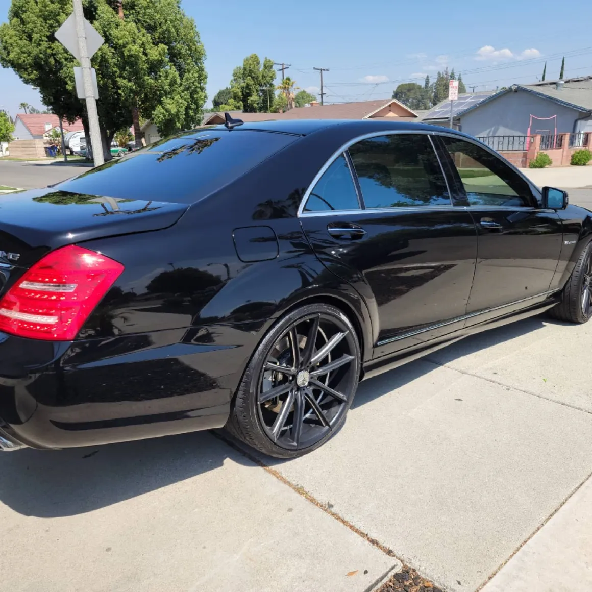 Black sedan with custom wheels parked on residential street