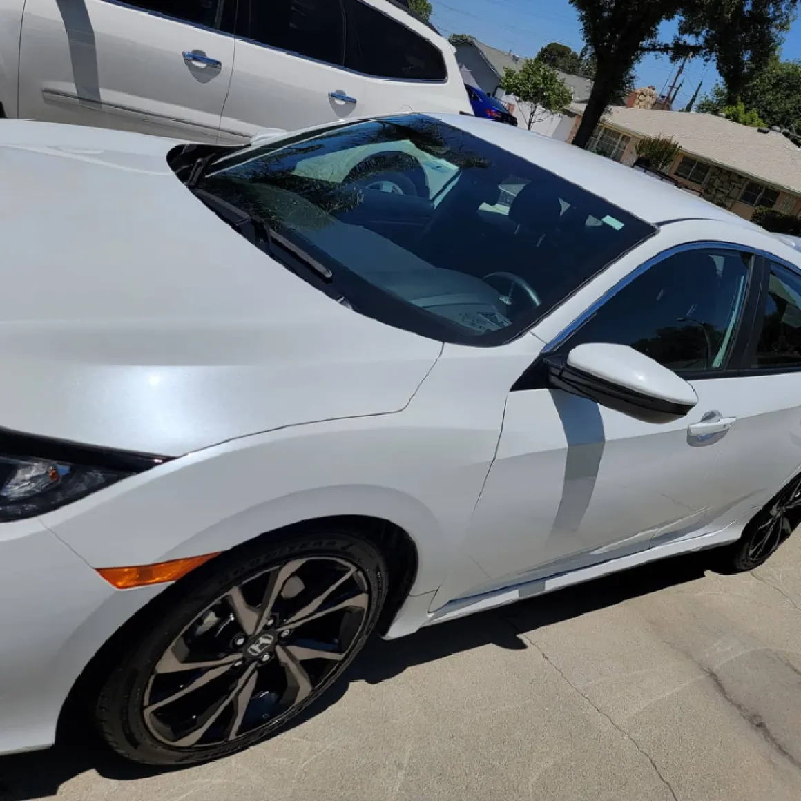 White car with tinted windshield parked in residential driveway