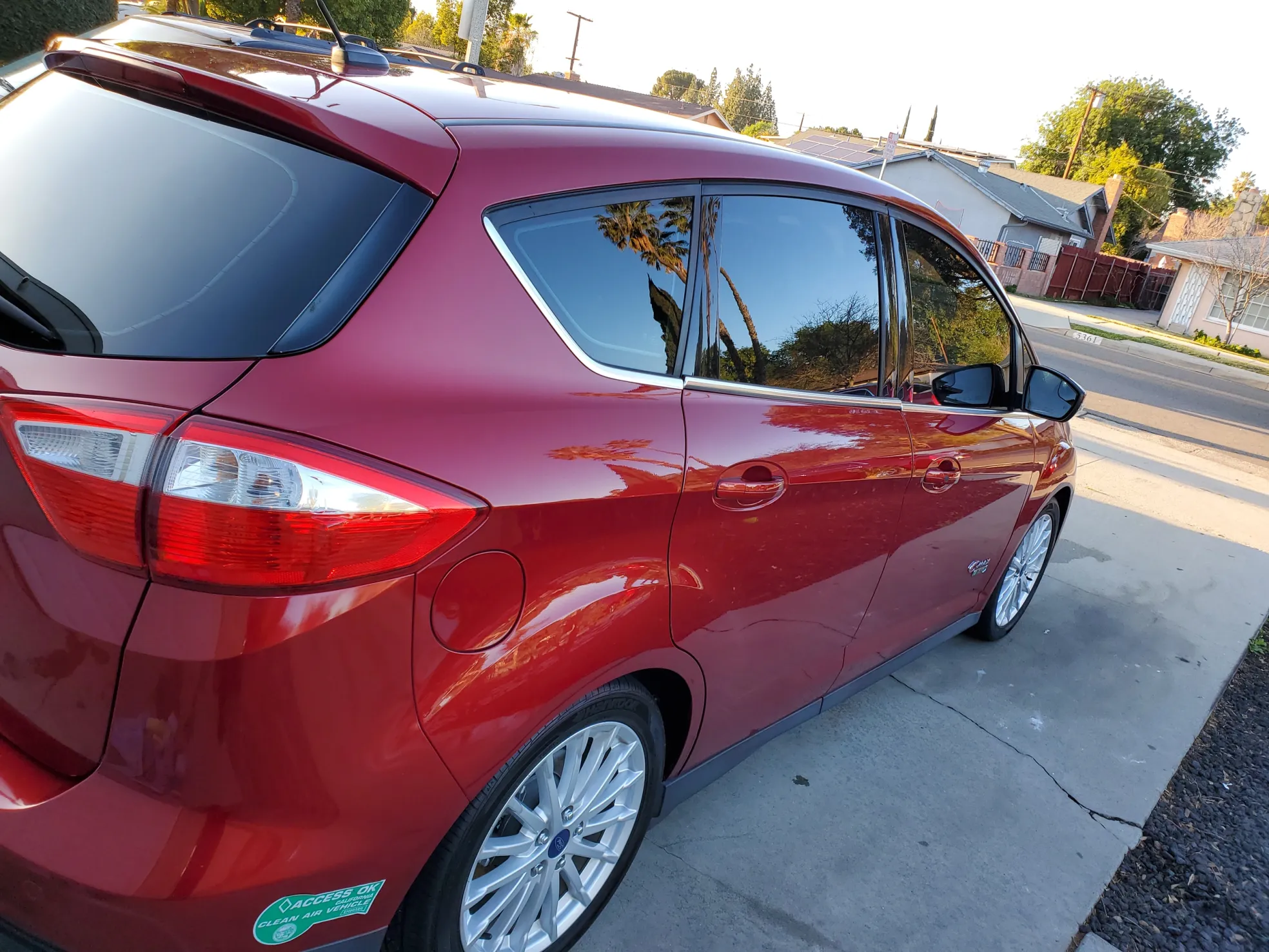 Red Ford C-Max minivan parked on residential street, side profile view