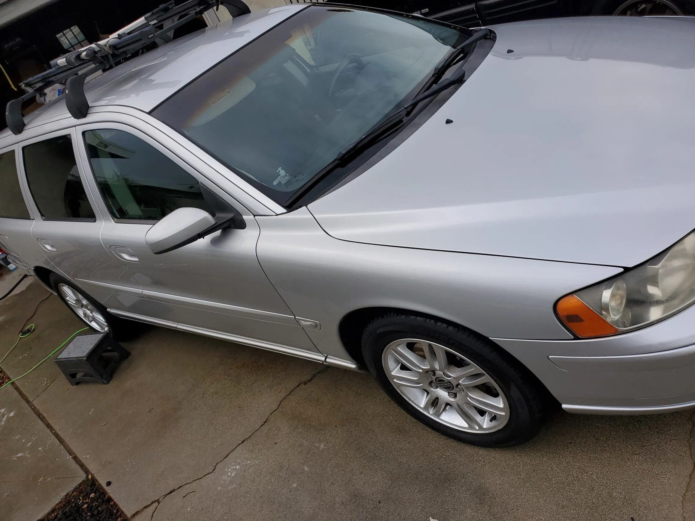 Silver sedan parked in garage with sunroof open and roof rack installed