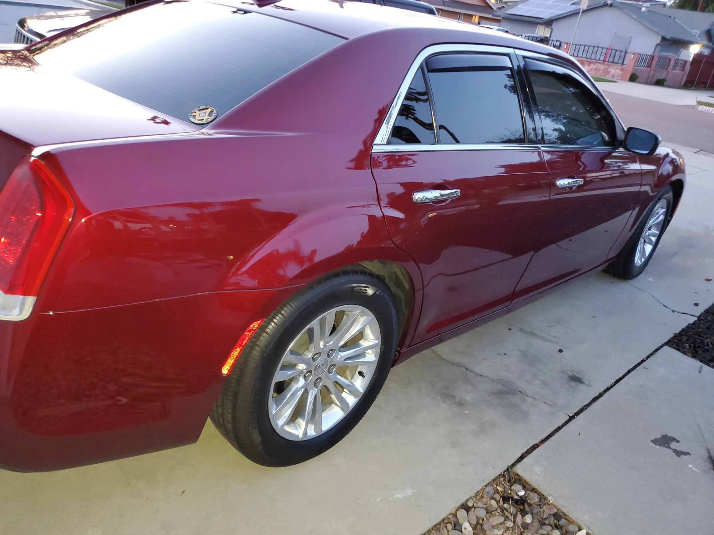 Burgundy Cadillac sedan parked on residential driveway with chrome wheels