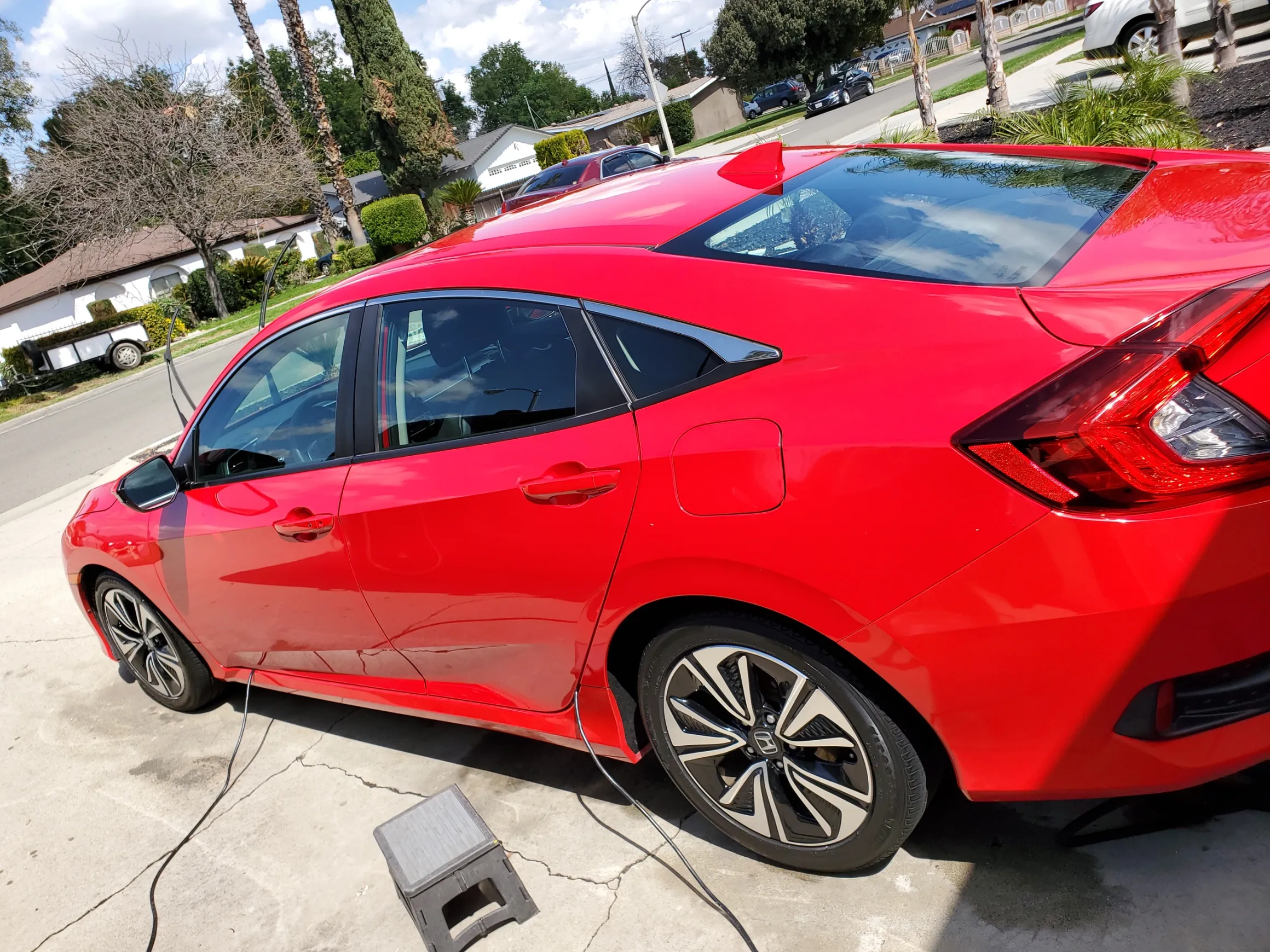 Red Honda Civic parked in residential driveway with charging cable connected
